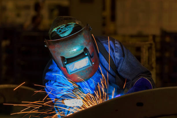 worker is welding metal part in car factory